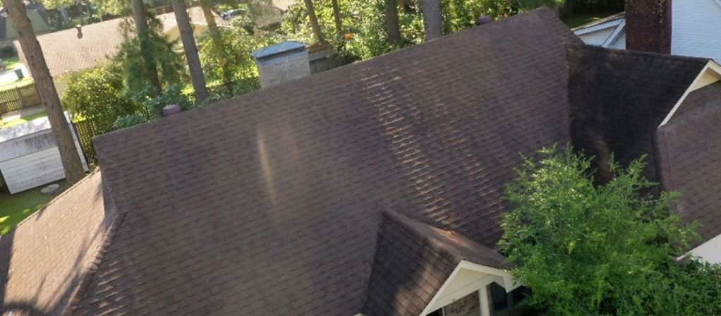 Before: Roof covered in black algae streaks cleaned back to tan shingles in central Arkansas