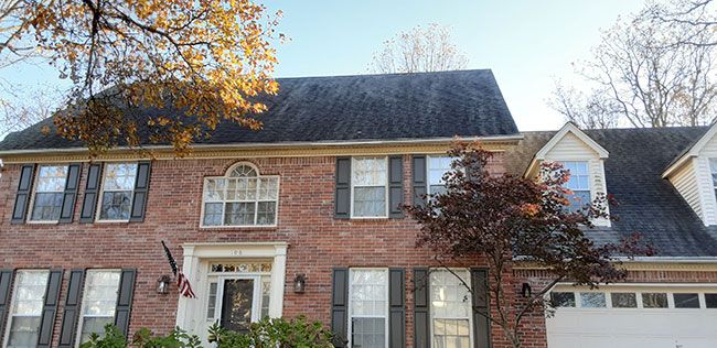 Before: Brick colonial home with dormers after roof cleaning in the Little Rock area