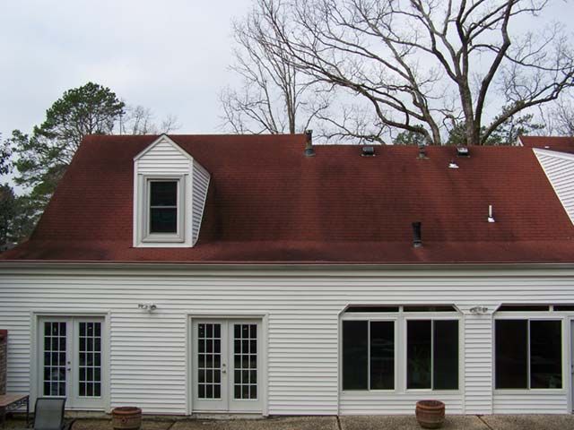 Before: Red roof with dormers restored to its original color by roof cleaning near Little Rock AR
