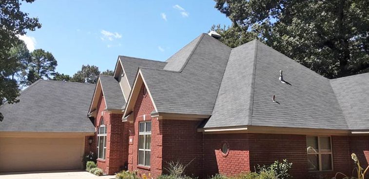 After: Brick home with streaked gray shingles after roof stain removal in central Arkansas